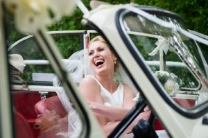 a bride laughing in her open top vintage wedding car